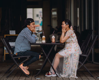 Woman sitting on table at sidewalk cafe