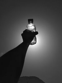 Close-up of hand holding illuminated light against sky