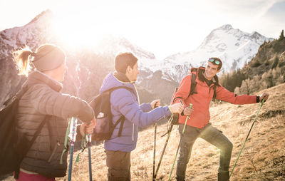 Friends standing on snow covered mountain against sky