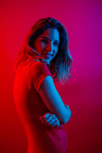 Portrait of smiling young woman against red background