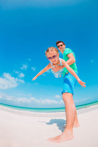 Low angle view of people at beach against blue sky