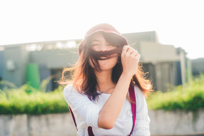 Portrait of beautiful young woman standing against blurred background