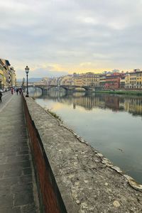 Bridge over river by buildings in city against sky