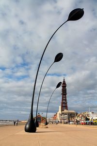 Decoration on promenade with blackpool tower against cloudy sky