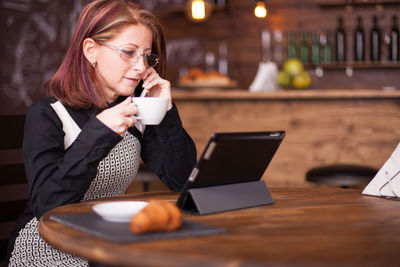 Young woman using laptop while sitting on table