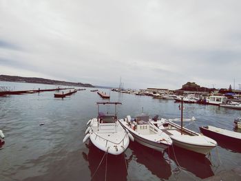 Boats moored at harbor against sky