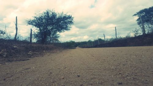 Surface level of road passing through landscape against cloudy sky