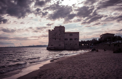 Buildings on beach against sky during sunset