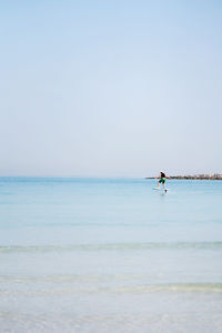 Man doing e foiling around people paddle boarding