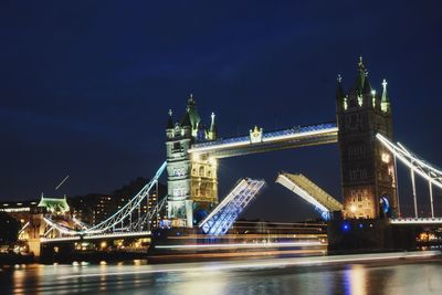 Illuminated bridge over river at night