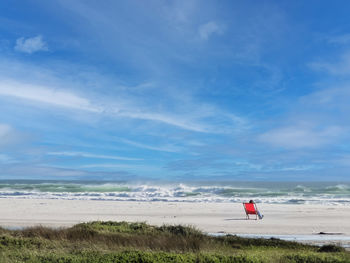 Rear view of woman standing at beach against sky