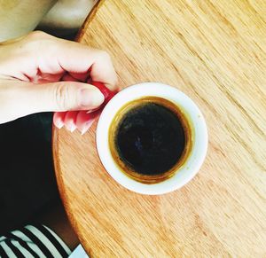 Directly above shot of hand holding tea cup on table