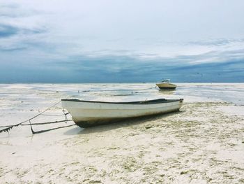 Boat moored on beach against sky