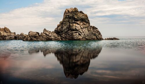 Rock formation in sea against sky