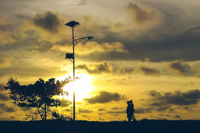 Silhouette man on street against sky during sunset