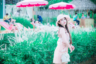 Portrait of young woman standing against plants