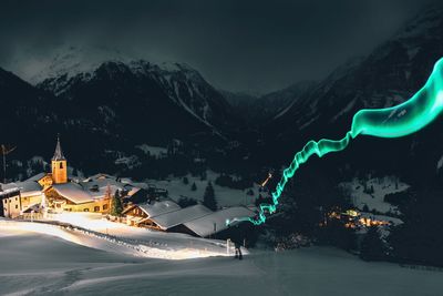 Person with light painting in town against mountains during winter