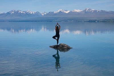 Full length of a woman doing yoga on rock in lake 