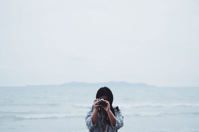 Rear view of man on beach against sky