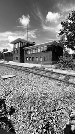 Railroad tracks by abandoned building against sky