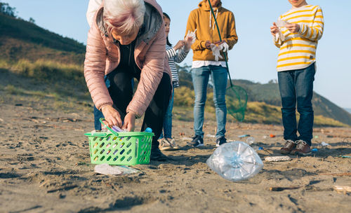 People cleaning beach against sky