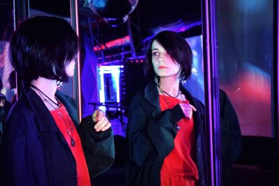 Beautiful woman reflecting in illuminated mirror during event