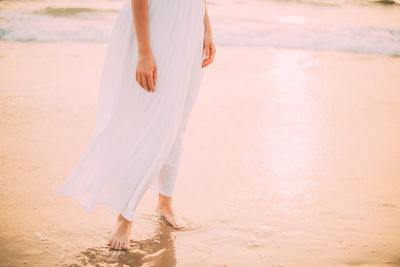 Low section of woman standing at beach