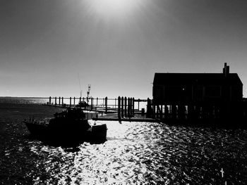 Silhouette built structure on beach against clear sky