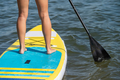 Caucasian woman swims on a sup board. close-up of female legs on the surf.