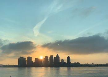 Scenic view of sea by buildings against sky during sunset