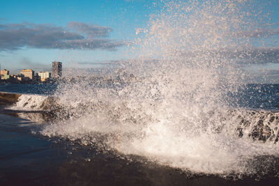 Waves splashing in sea against sky