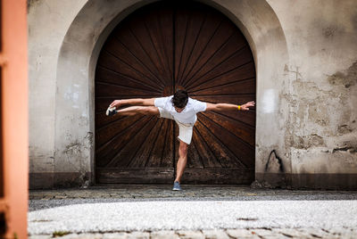 Young man exercising against door