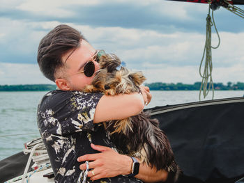 Handsome man hugging and kissing his small dog yorkshire terrier