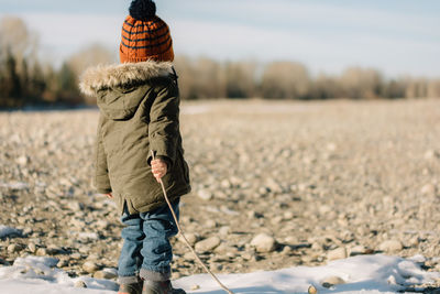 Low section of boy standing on snow covered landscape