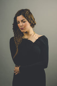 Young woman looking away while standing against wall