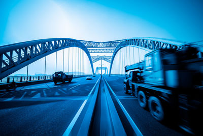 Vehicles on bridge against clear blue sky