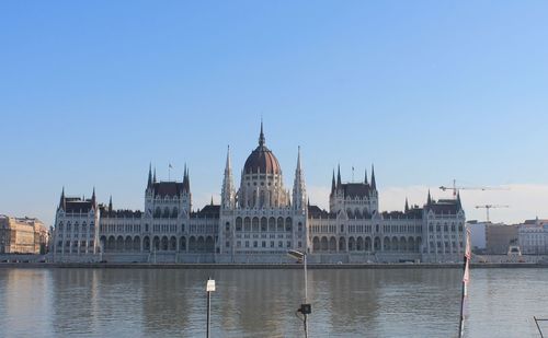 Hungarian parliament building by river against blue sky