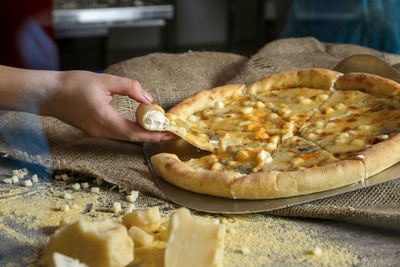 Cropped image of woman hand having pizza at table