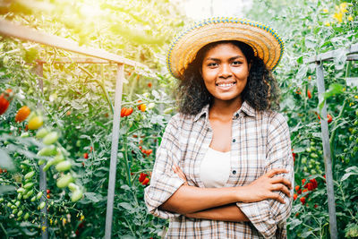 Portrait of young woman standing amidst plants