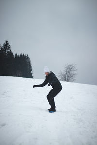 Young dark-skinned man sits on a wooden historic sledge and after a ride looks back at the hill