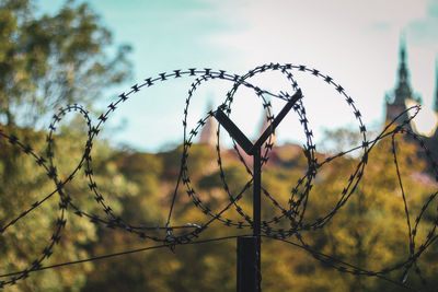 Barbed wire fence in city against sky