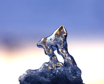 Close-up of snow on rock against sky