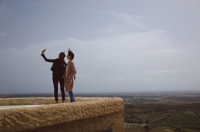 Friends standing on land against sky