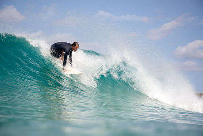 Man surfing in sea against sky