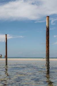 Wooden post in sea against sky