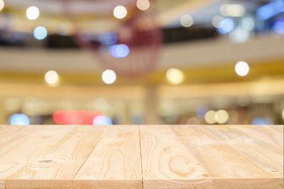 Close-up of empty wooden table in illuminated shopping mall