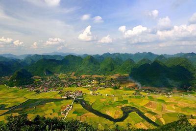 Scenic view of agricultural field against cloudy sky