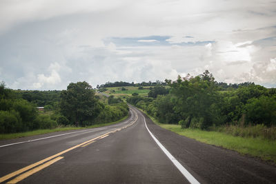 Road by trees against sky