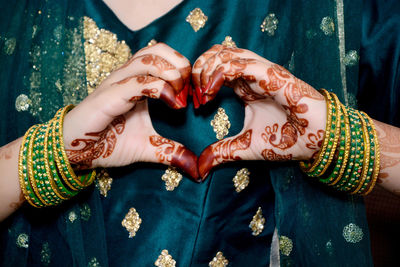 An indian bride making heart shape by her hands.