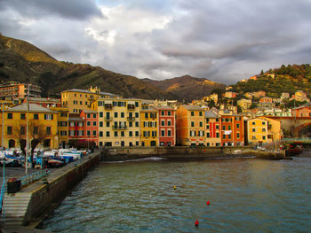 Buildings by river against sky in city